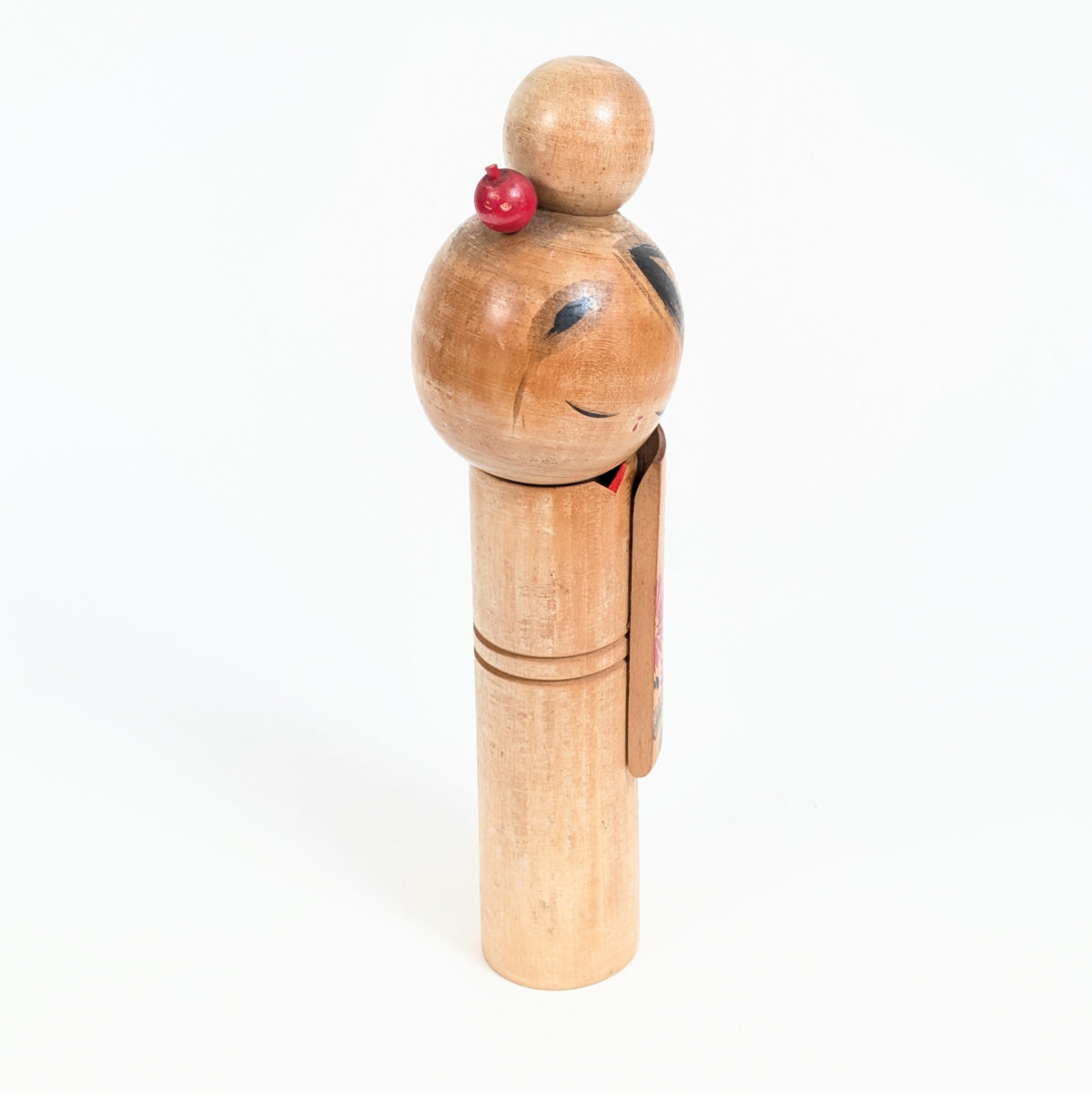 Profil d'une poupée japonaise en bois de style sōsaku kokeshi, visage incliné et longue manche de kimono décorée