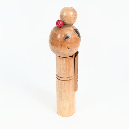 Profil d'une poupée japonaise en bois de style sōsaku kokeshi, visage incliné et longue manche de kimono décorée