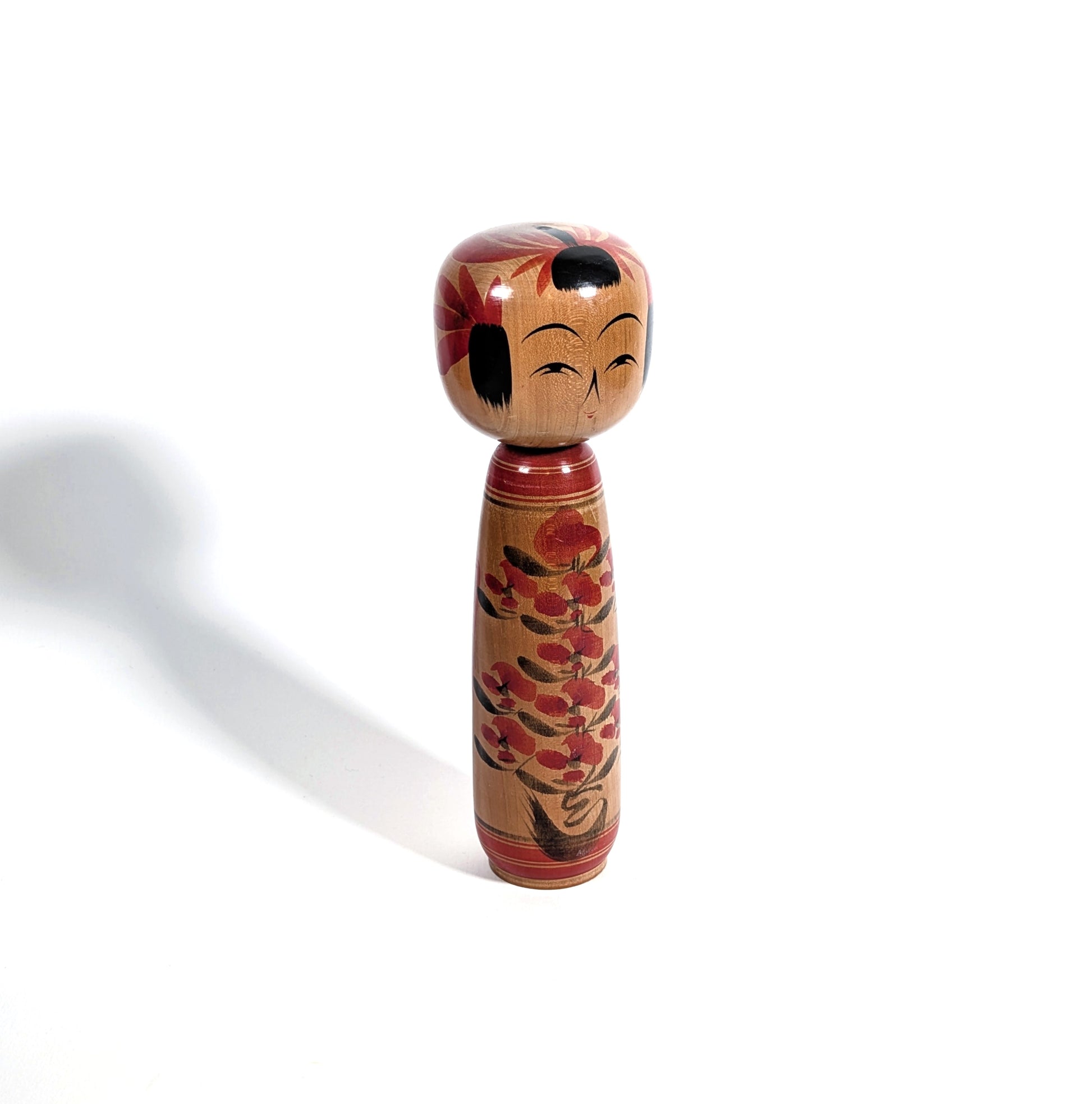Poupée japonaise kokeshi en bois peint, vue de profil, décor floral traditionnel, artisanat japonais de l’école Yamagata

