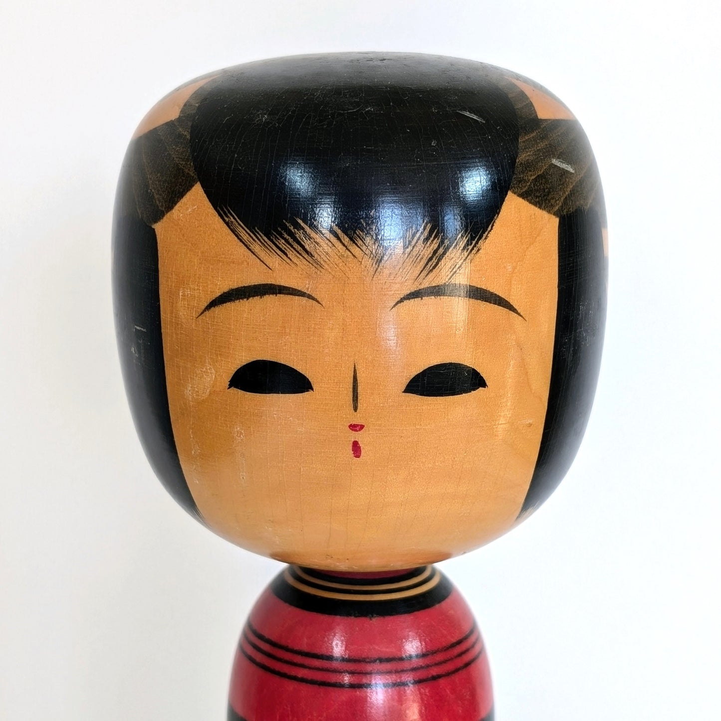 Gros plan sur le visage peint d’une poupée japonaise kokeshi en bois, artisan Sasaki Katsumi