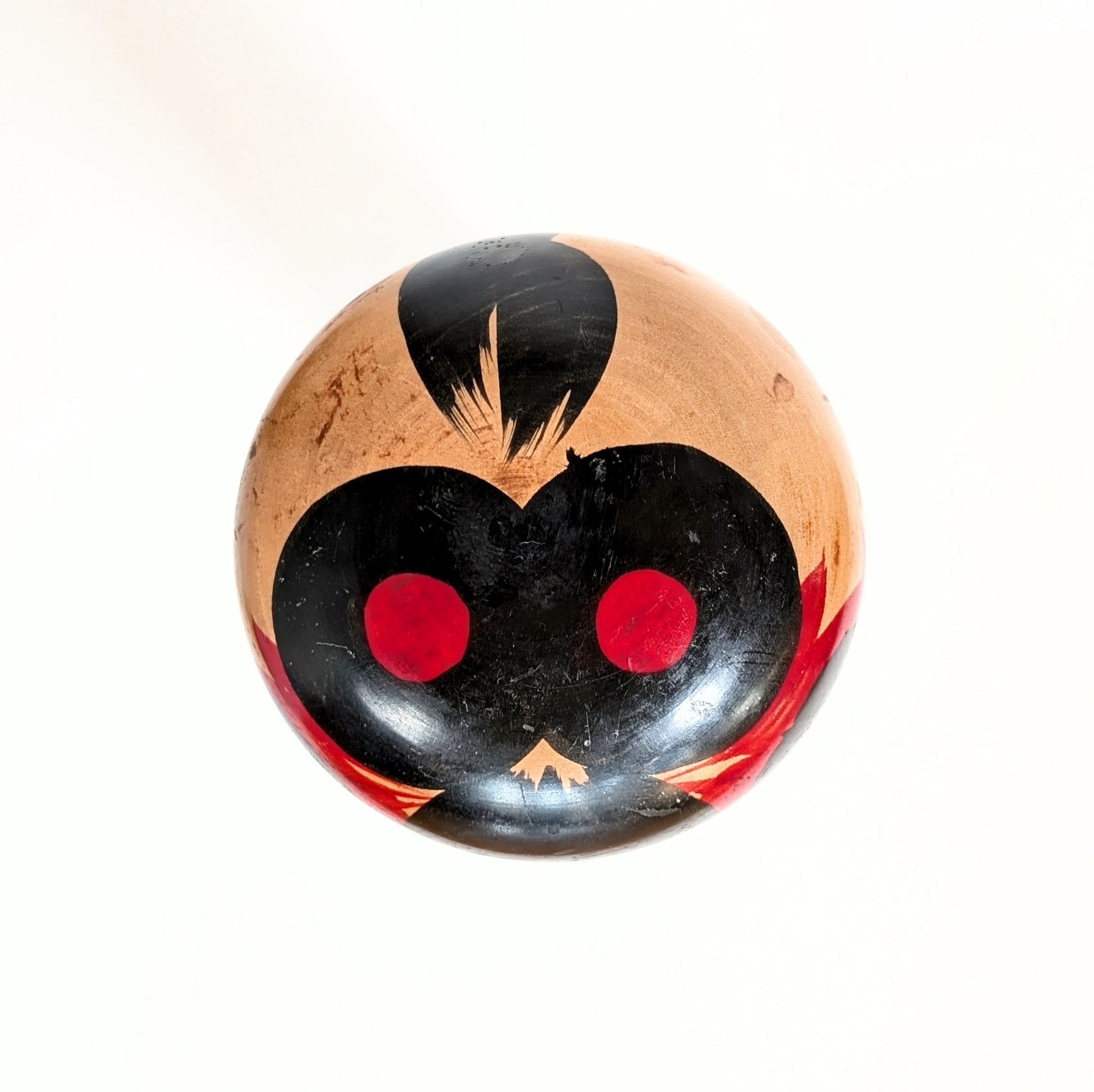 Vue du dessus de la tête d’une poupée japonaise kokeshi shingata ancienne par Kiyohara Takao, peinture noire et rouge