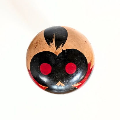 Vue du dessus de la tête d’une poupée japonaise kokeshi shingata ancienne par Kiyohara Takao, peinture noire et rouge