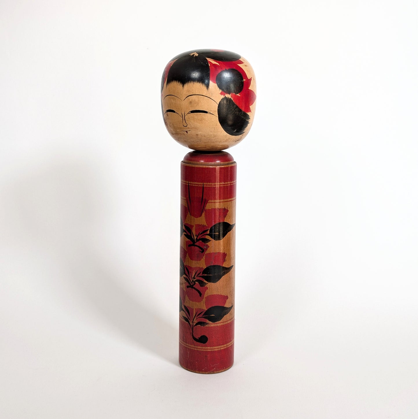Vue latérale d’une poupée japonaise kokeshi shingata ancienne de Kiyohara Takao, décor floral camélia