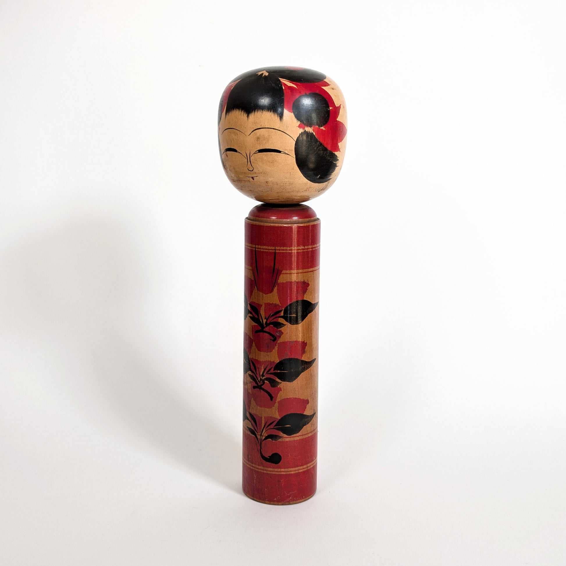 Vue latérale d’une poupée japonaise kokeshi shingata ancienne de Kiyohara Takao, décor floral camélia