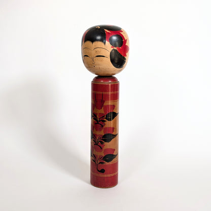 Vue latérale d’une poupée japonaise kokeshi shingata ancienne de Kiyohara Takao, décor floral camélia