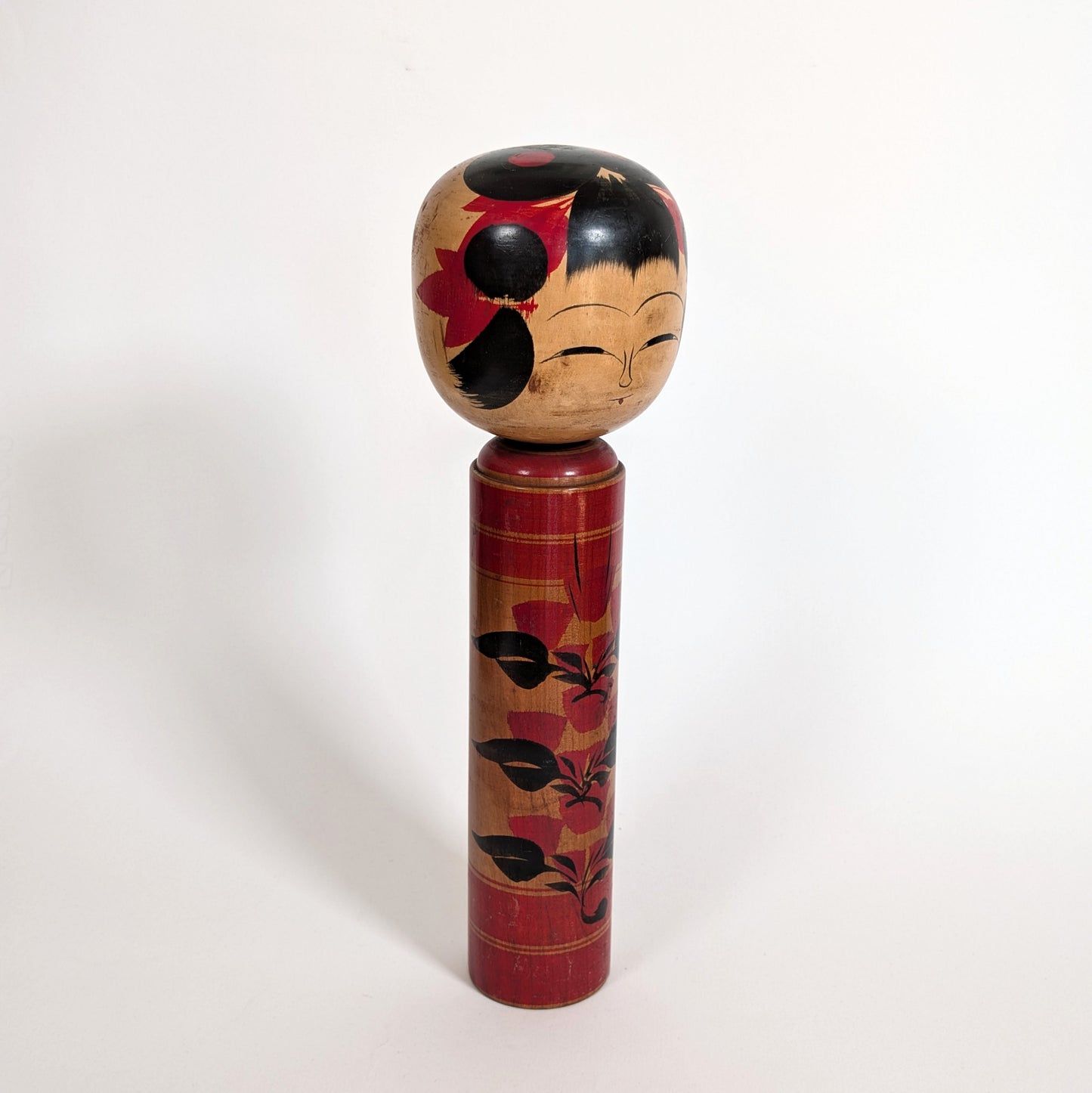 Poupée japonaise kokeshi shingata ancienne par Kiyohara Takao, vue trois-quarts, visage traditionnel et motifs camélia