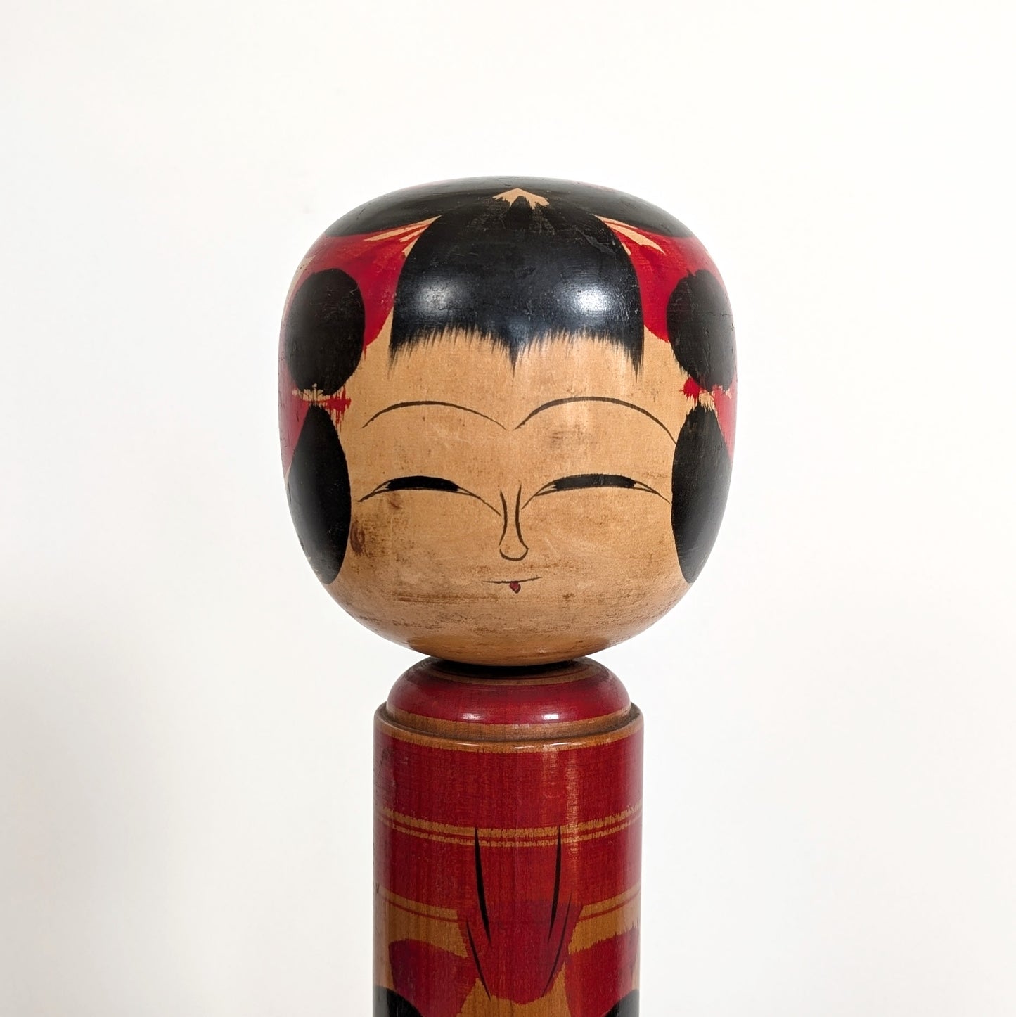 Détail du visage d’une poupée japonaise kokeshi shingata ancienne par Kiyohara Takao, expression douce et peinture traditionnelle