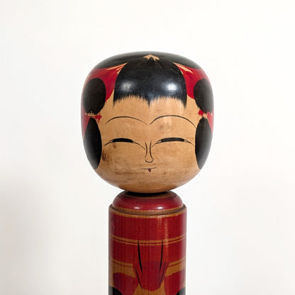 Détail du visage d’une poupée japonaise kokeshi shingata ancienne par Kiyohara Takao, expression douce et peinture traditionnelle