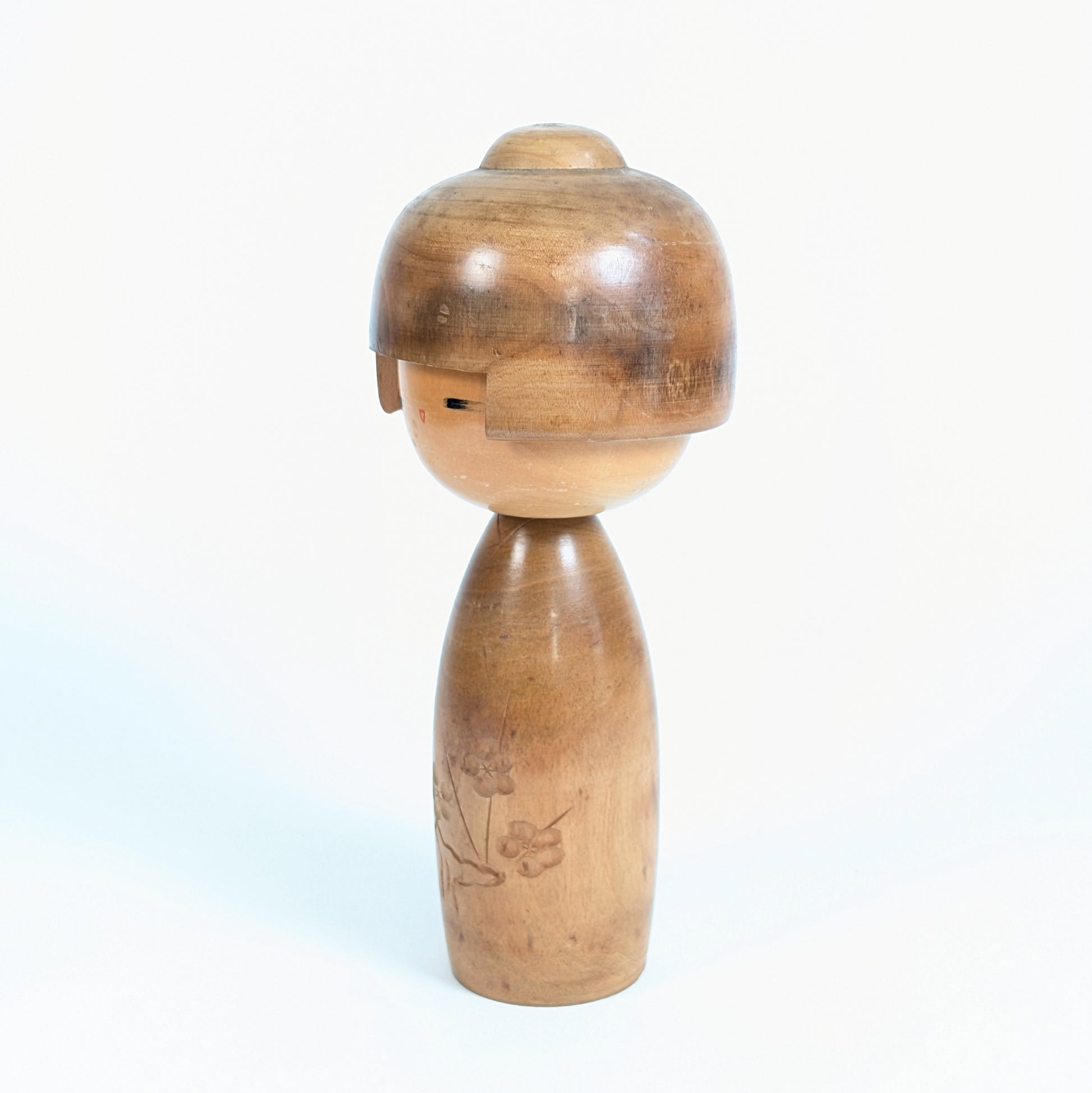 Poupée kokeshi japonaise de Fujikawa Masae vue de trois-quarts, avec coiffure sculptée dans le bois