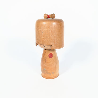 Poupée kokeshi japonaise signée Ueda Izumi, art populaire japonais en bois avec expression douce et motif floral rouge