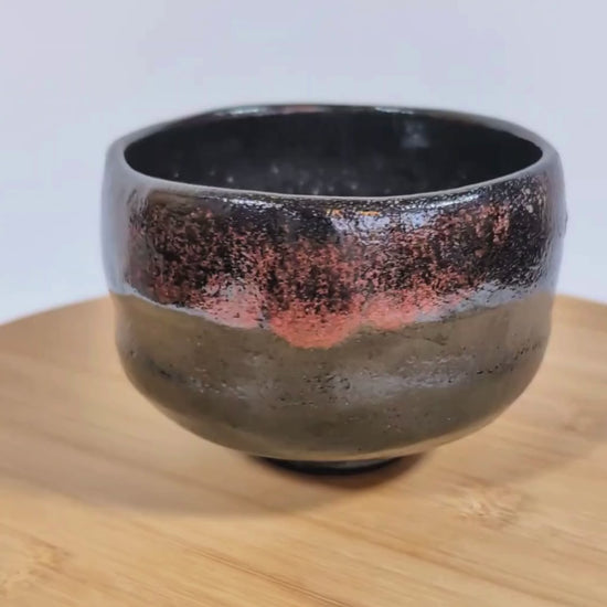 Vidéo 360° d’un chawan en kuro raku signé Sasaki Shoraku, tournant sur un plateau pour montrer la forme, la texture et la glaçure raku noire.