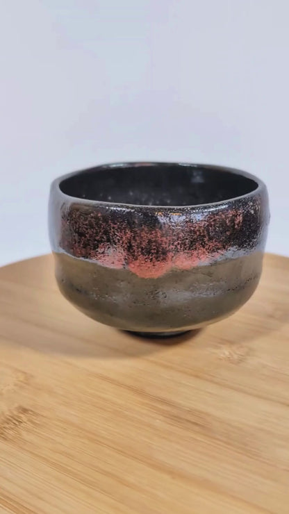 Vidéo 360° d’un chawan en kuro raku signé Sasaki Shoraku, tournant sur un plateau pour montrer la forme, la texture et la glaçure raku noire.