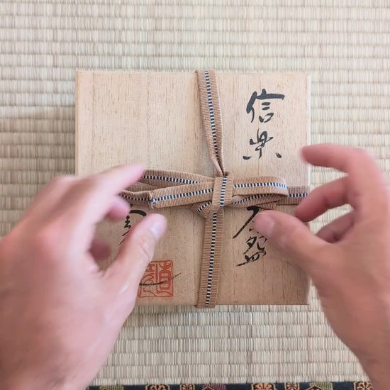 Présentation du chawan Shigaraki de Naohiko Koyama, bol à matcha japonais artisanal aux effets yōhen, hi-iro et cendre, avec kōdai signé et tomobako.
