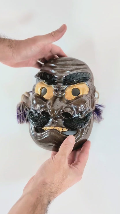 Vidéo de présentation du masque Nô japonais en céramique Kutani représentant Susanoo no Mikoto, signé Matsuda Sokawa, montrant les détails, reflets iridescents et cordelettes décoratives.