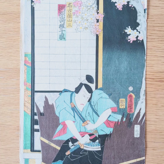 Vidéo détaillée d’une estampe japonaise originale de Kunisada Toyokuni III datée de 1861, représentant Kawarazaki Gonjuro I dans le rôle du samouraï Nagoya Sanza, avec sabres, costume kabuki, fleurs de cerisier, signature et sceaux.