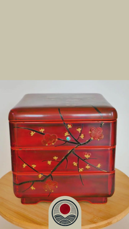 video de présensation d'une boite en laque Jubako en urushi rouge tournant sur un support. Elle présente des motifs de branches et fleurs de pruniers rouges. Maki-e et raden. Début 20ème siècle.
