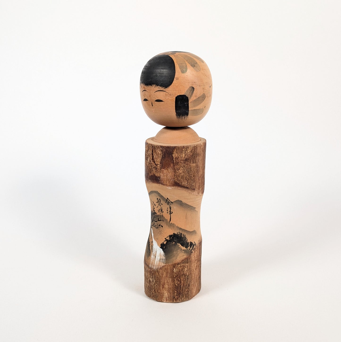 Vue de profil d’une kokeshi omiyage de Fukushima, décor sumi-e du Mont Bandai et silhouette en bois tourné de 25 cm.