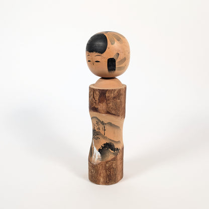 Vue de profil d’une kokeshi omiyage de Fukushima, décor sumi-e du Mont Bandai et silhouette en bois tourné de 25 cm.