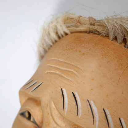 Gros plan sur le front ridé d’un masque de vieillard japonais Nô, incarnation de sagesse dans le théâtre classique.