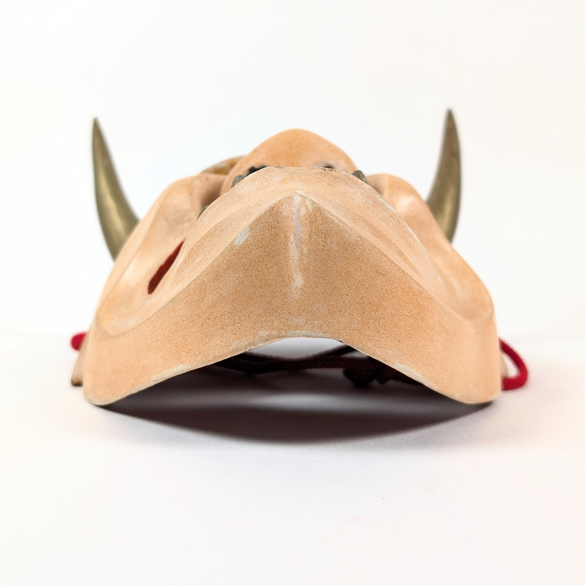Vue par-dessous du menton sculpté d'un masque japonais Hannya, révélant la courbure du visage et ses ouvertures.
