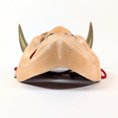 Vue par-dessous du menton sculpté d'un masque japonais Hannya, révélant la courbure du visage et ses ouvertures.