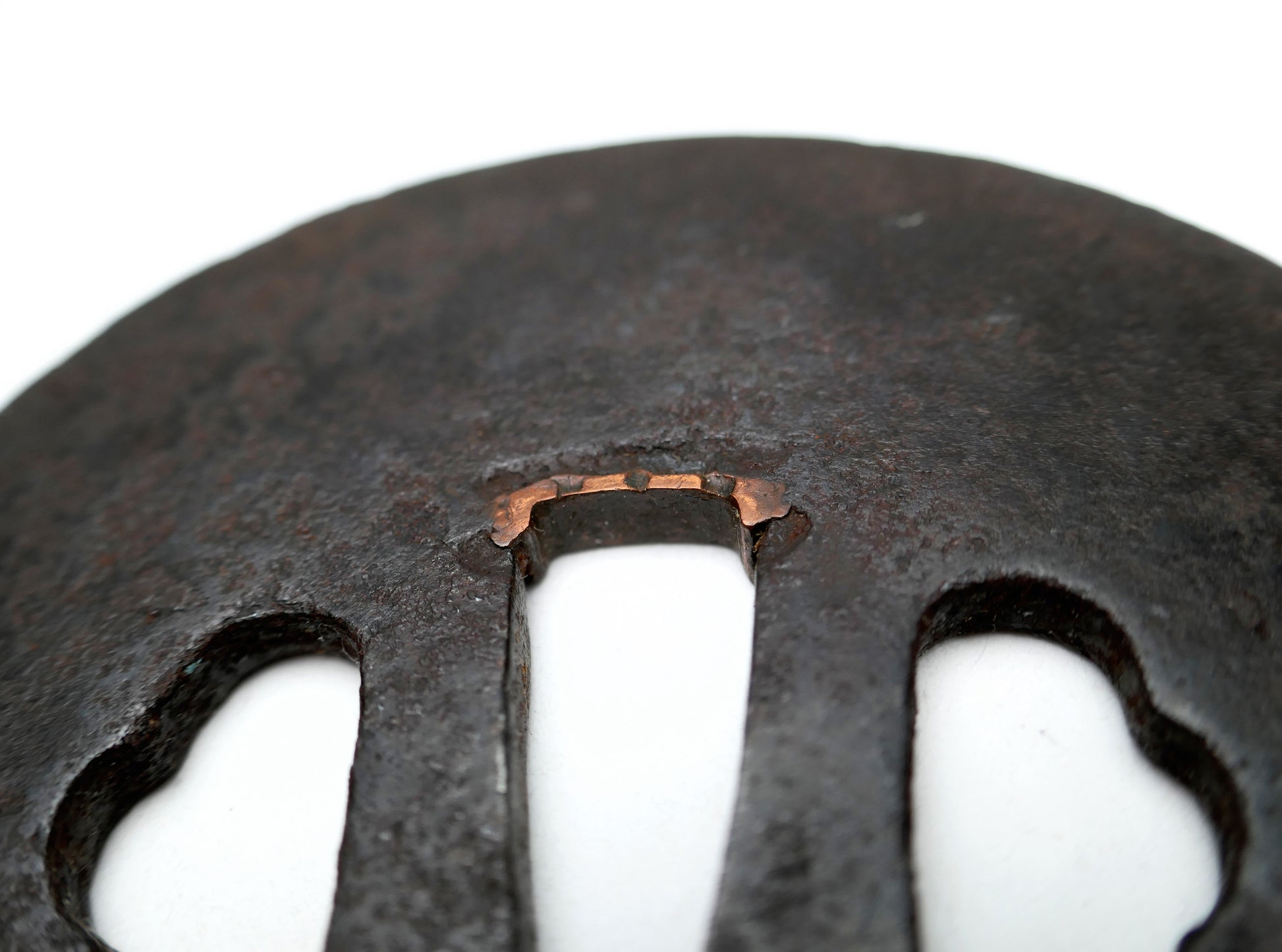 Gros plan des sekigane en cuivre ajustant le nakago-ana d’une tsuba japonaise antique en fer, ancienne garniture de nihontō.