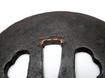 Gros plan des sekigane en cuivre ajustant le nakago-ana d’une tsuba japonaise antique en fer, ancienne garniture de nihontō.