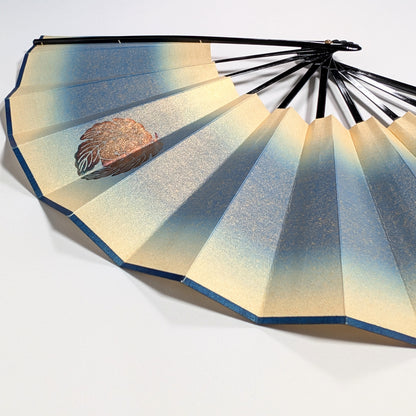 Détail d’un sensu japonais en papier irisé bleu et or avec motif floral doré, éventail pliant traditionnel.