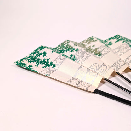 Détail du papier nacré d’un sensu japonais avec feuilles d’érable vert et lignes d’eau courante gris argenté.