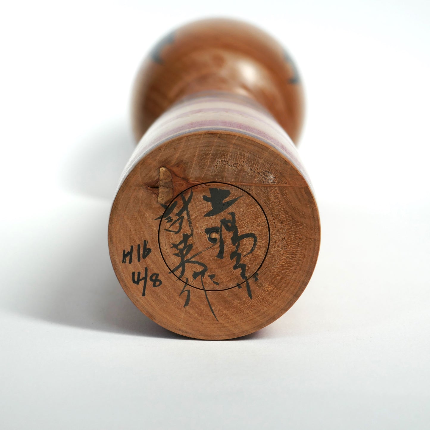 Signature d’Abe Kazue sous une poupée kokeshi japonaise Tsuchiyu, artisanat en bois tourné traditionnel.