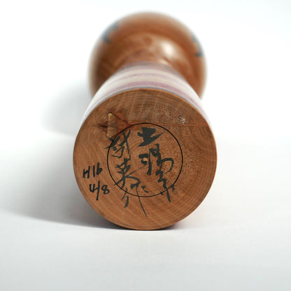Signature d’Abe Kazue sous une poupée kokeshi japonaise Tsuchiyu, artisanat en bois tourné traditionnel.