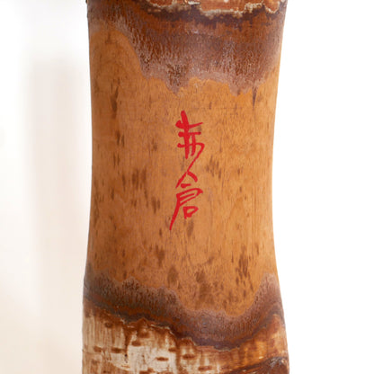 Détail de la signature en kanji rouge "Akakura" sur une kokeshi japonaise ancienne.