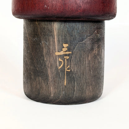 Détail de la signature calligraphiée de l’artiste japonais Sansaku Sekiguchi sur une poupée kokeshi sōsaku
