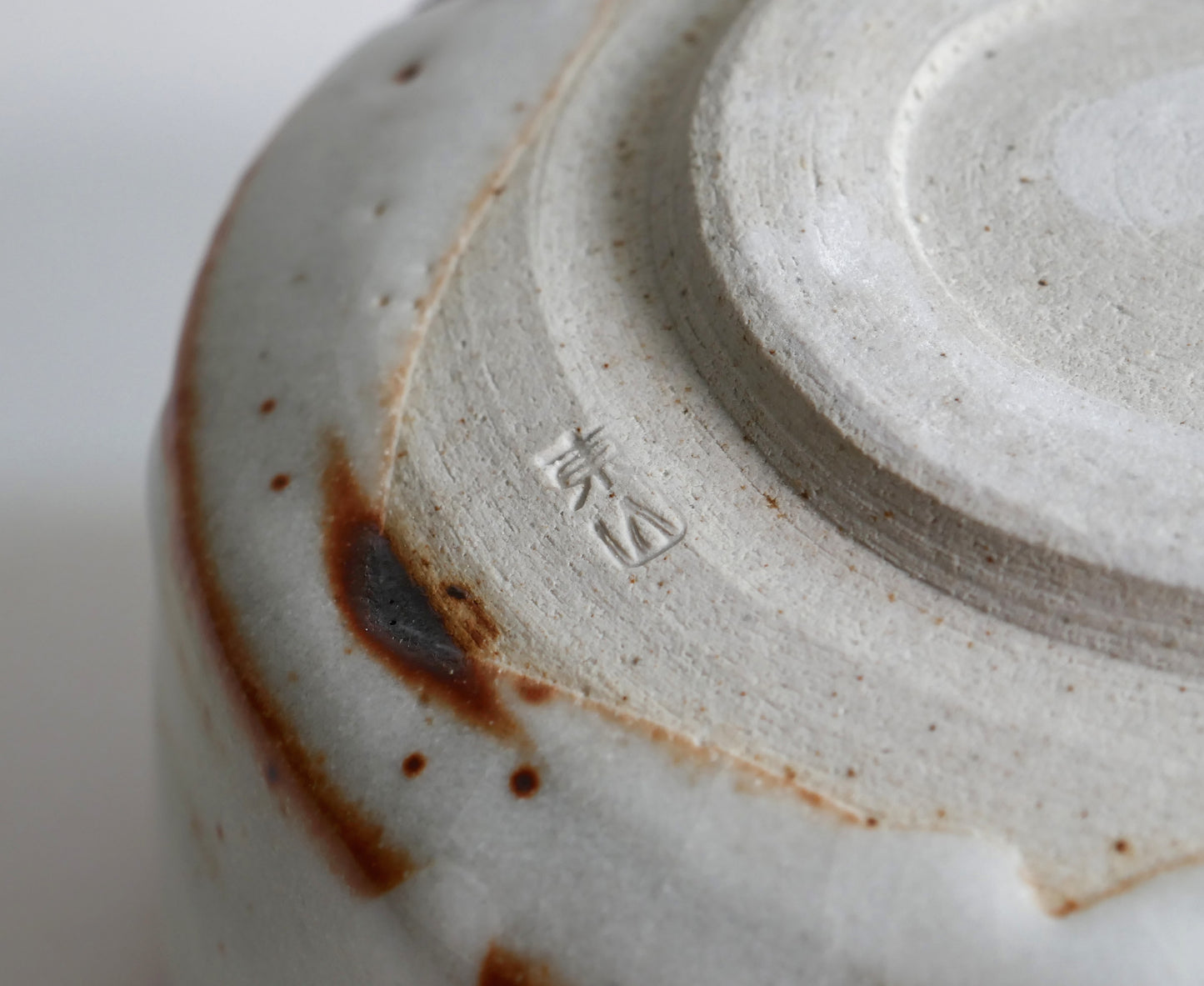 Signature sous le chawan Beni Shino, pied tourné d’un bol matcha japonais en céramique Shino authentique.