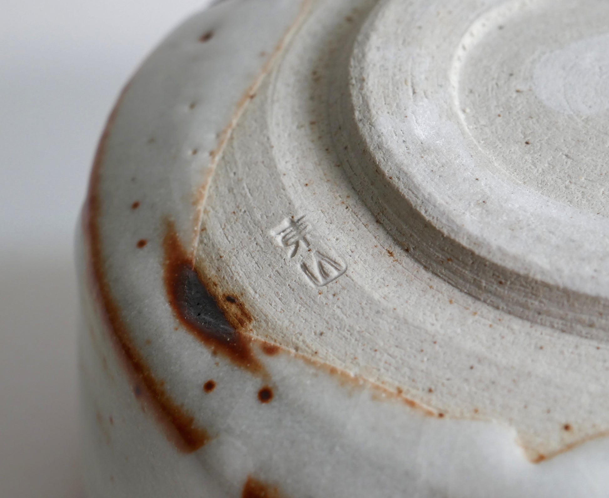 Signature sous le chawan Beni Shino, pied tourné d’un bol matcha japonais en céramique Shino authentique.