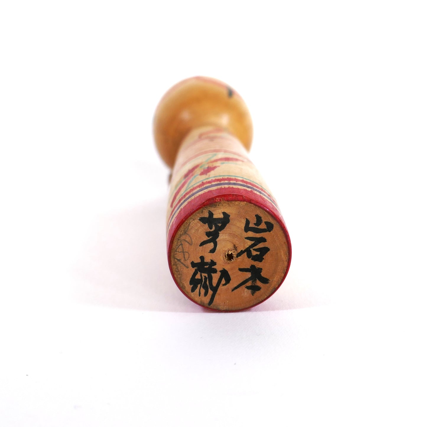 Signature artisanale d'Iwamoto Yoshizō sur le socle d'une kokeshi de style Nakanosawa.