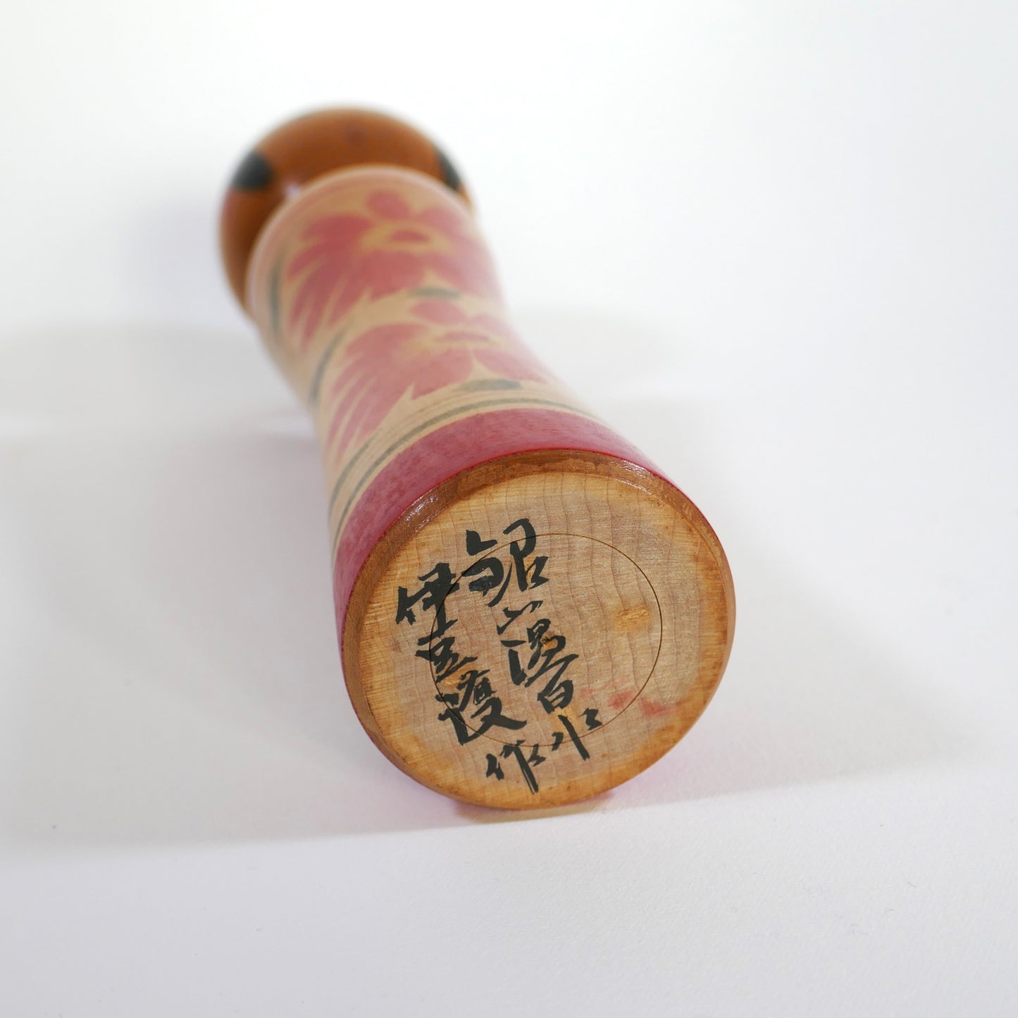 Signature de l'artisan Mamoru Izu sur une kokeshi Oshin japonaise – inscription Ginzan Onsen