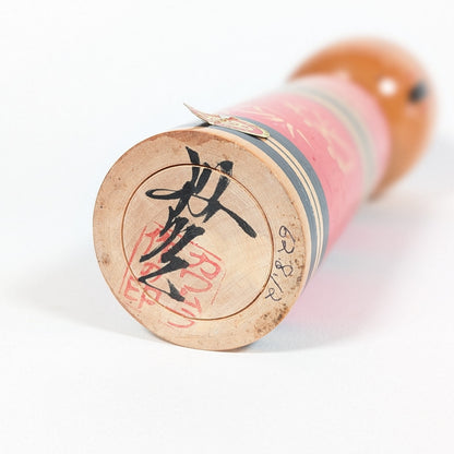 Signature et cachet sous la base d’une kokeshi de Kawamura Shōji, artisan japonais de kokeshi sosaku