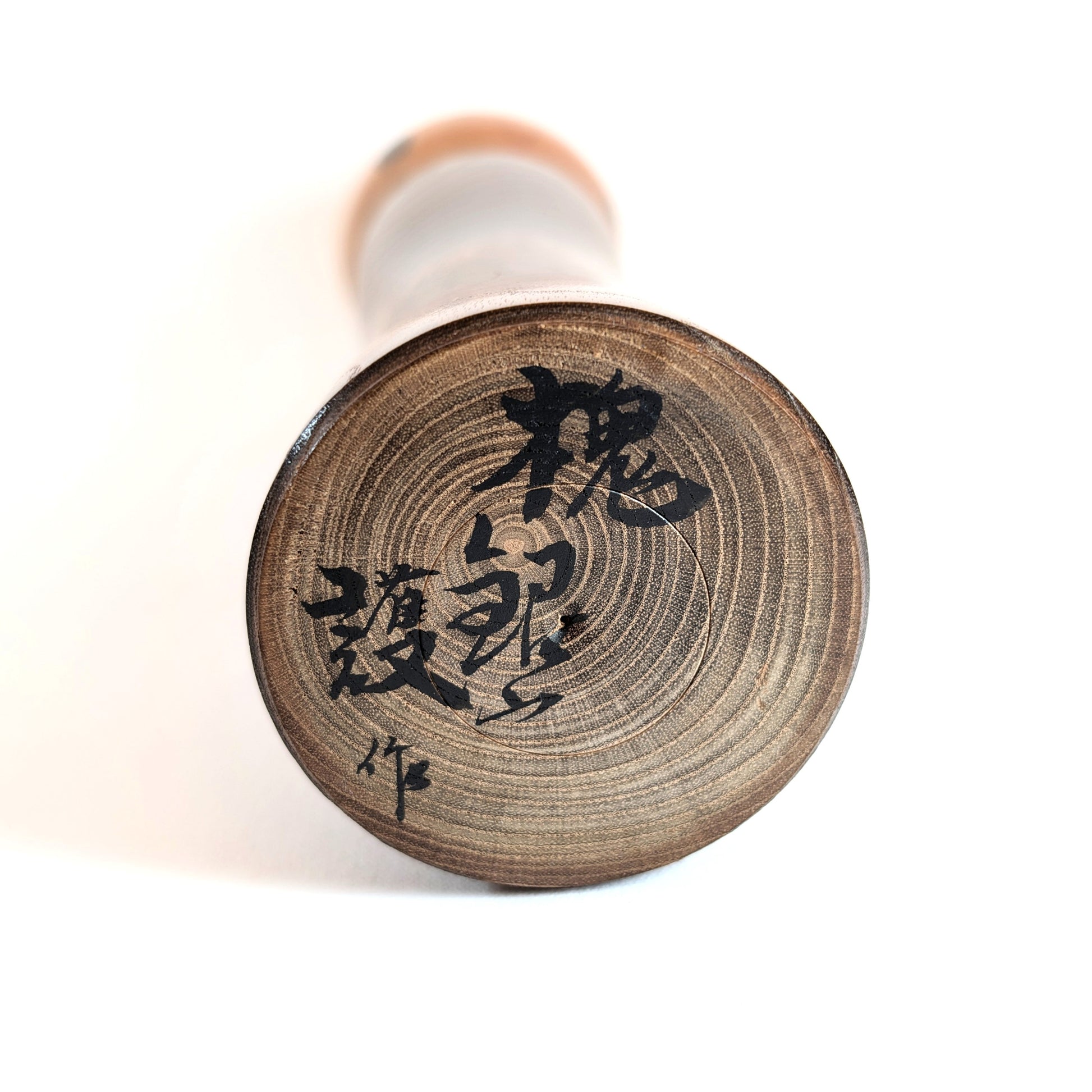 Signature artisanale de Mamoru Izu sous une kokeshi traditionnelle japonaise en bois