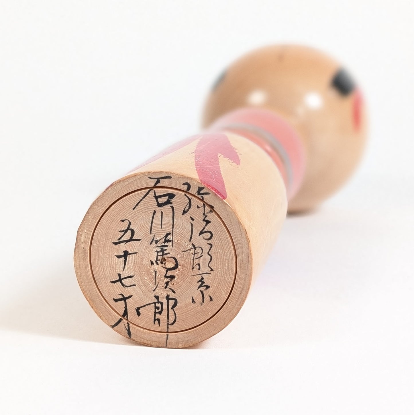Base signée d’une kokeshi Yajiro-kei par Ishikawa Tokujiro, avec inscription de l’artisan à 57 ans, vers 1972-1973