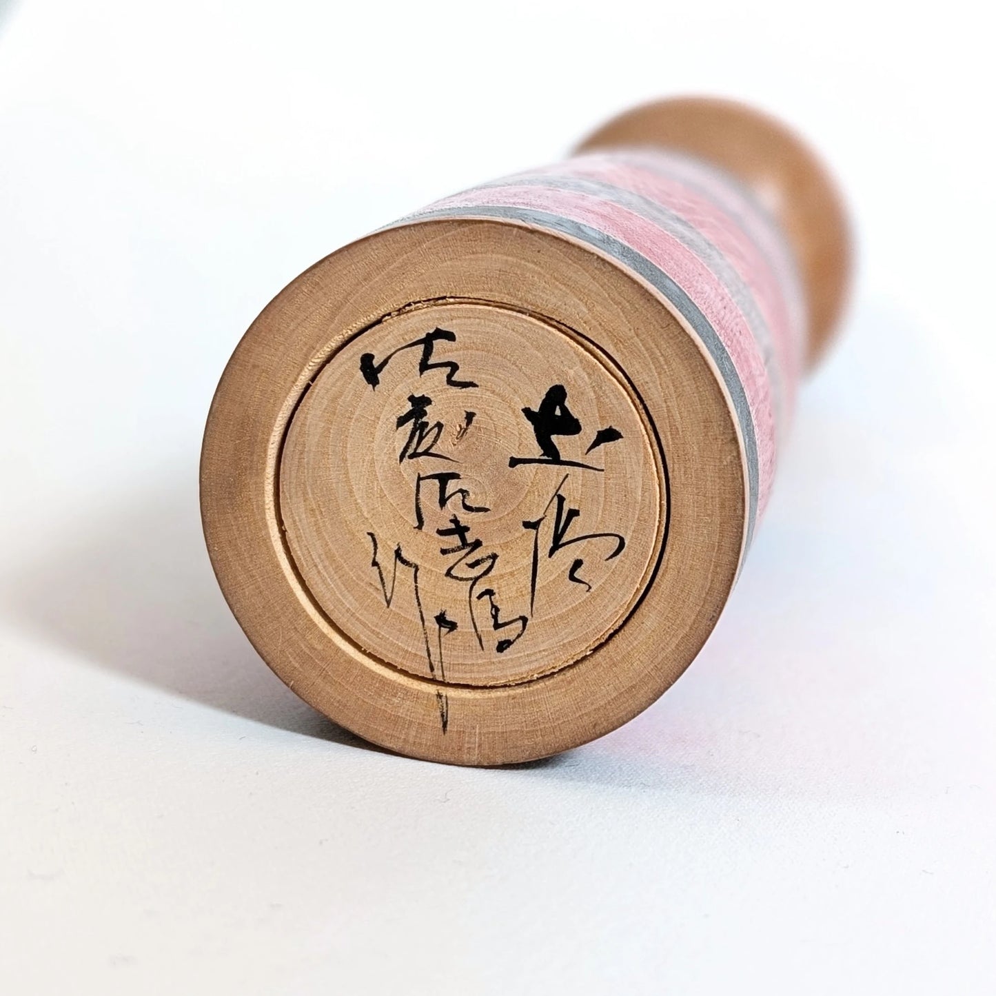 Signature manuscrite de l’artisan japonais Satō Sashima 佐藤佐志馬 sous une kokeshi traditionnelle Shōwa