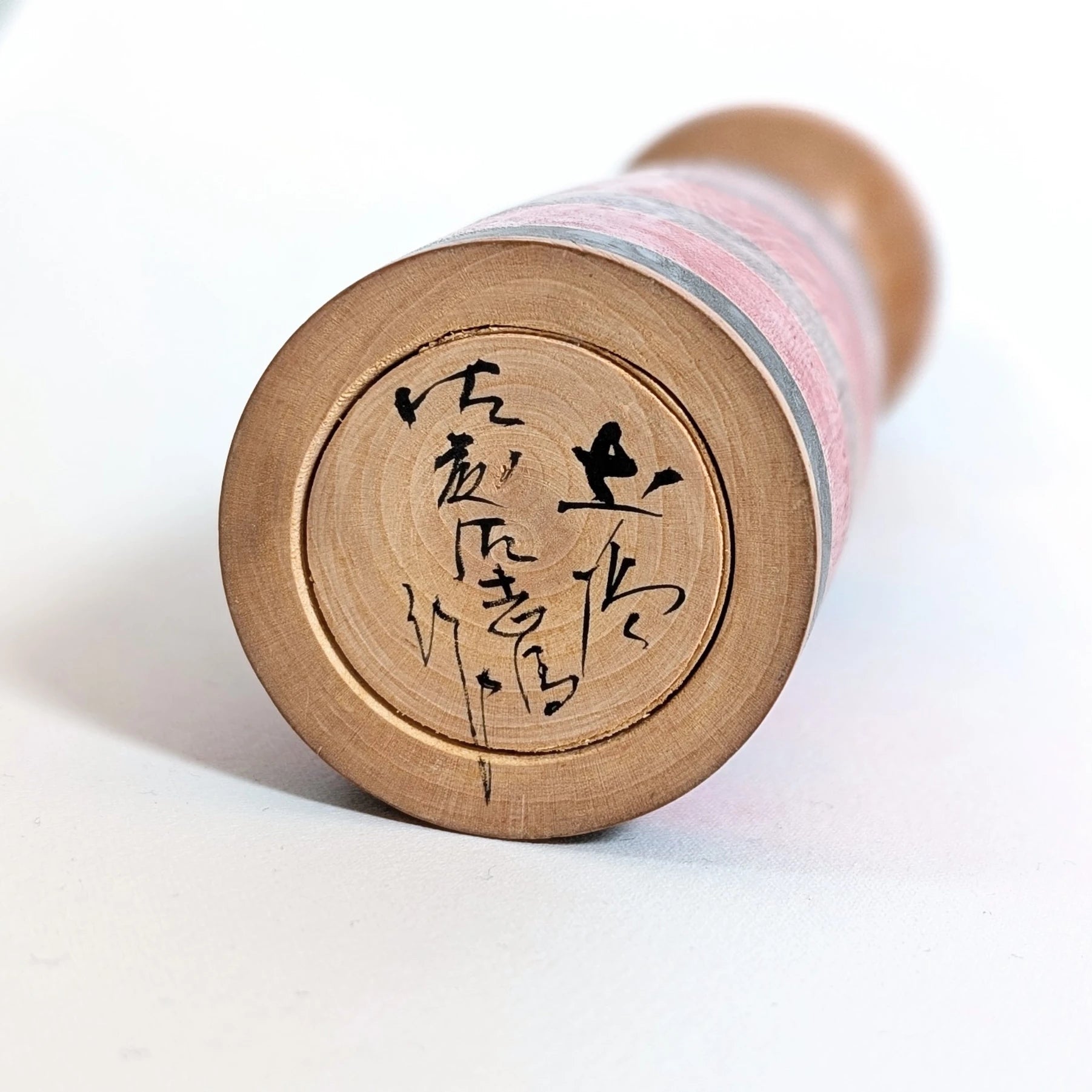 Signature manuscrite de l’artisan japonais Satō Sashima 佐藤佐志馬 sous une kokeshi traditionnelle Shōwa