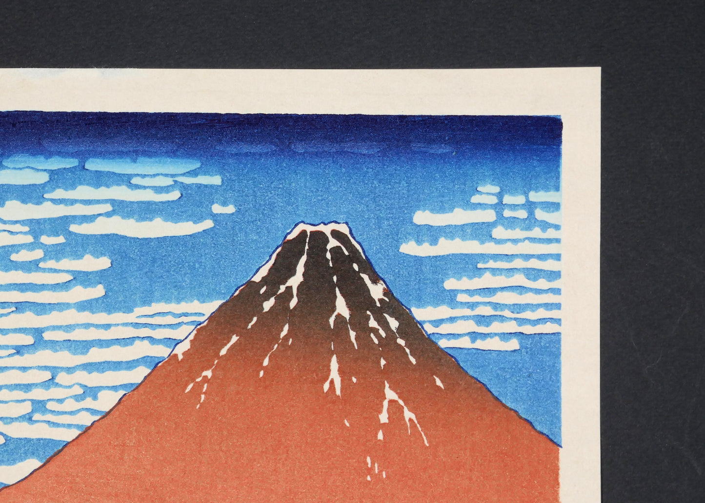 Gros plan sur le sommet enneigé du Fuji rouge et les nuagesde l’ukiyo-e de Hokusai.