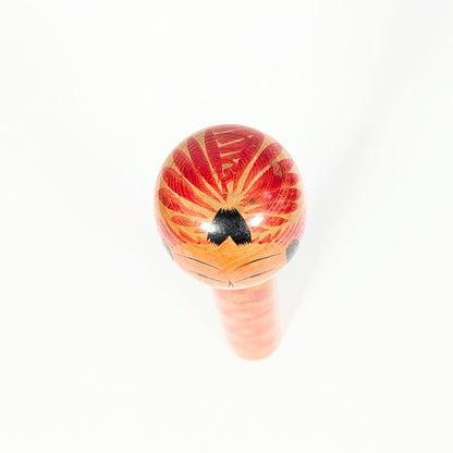 Vue du sommet de la tête d’une kokeshi Togatta, motif tegara rouge traditionnel, mèche noire et peinture artisanale japonaise.