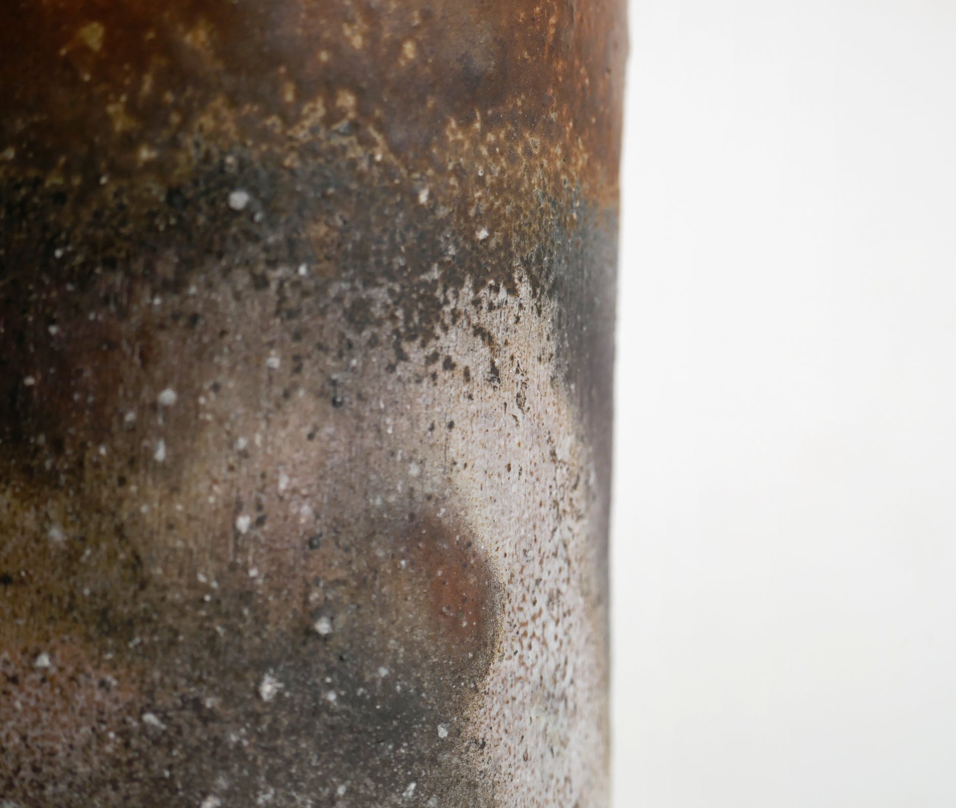 Gros plan sur les effets goma et sangiri de la surface d’un vase Bizen-yaki artisanal aux tons gris et bruns