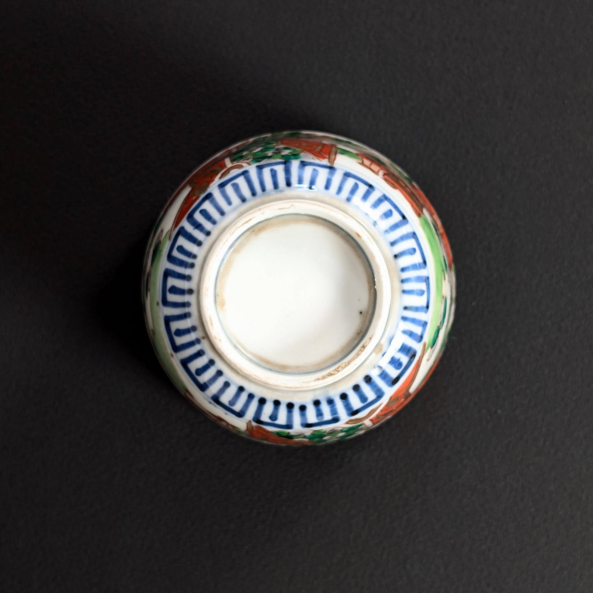 Dessous de tasse Imari ancienne avec pied annulaire, frise bleue au cobalt et traces de cuisson.