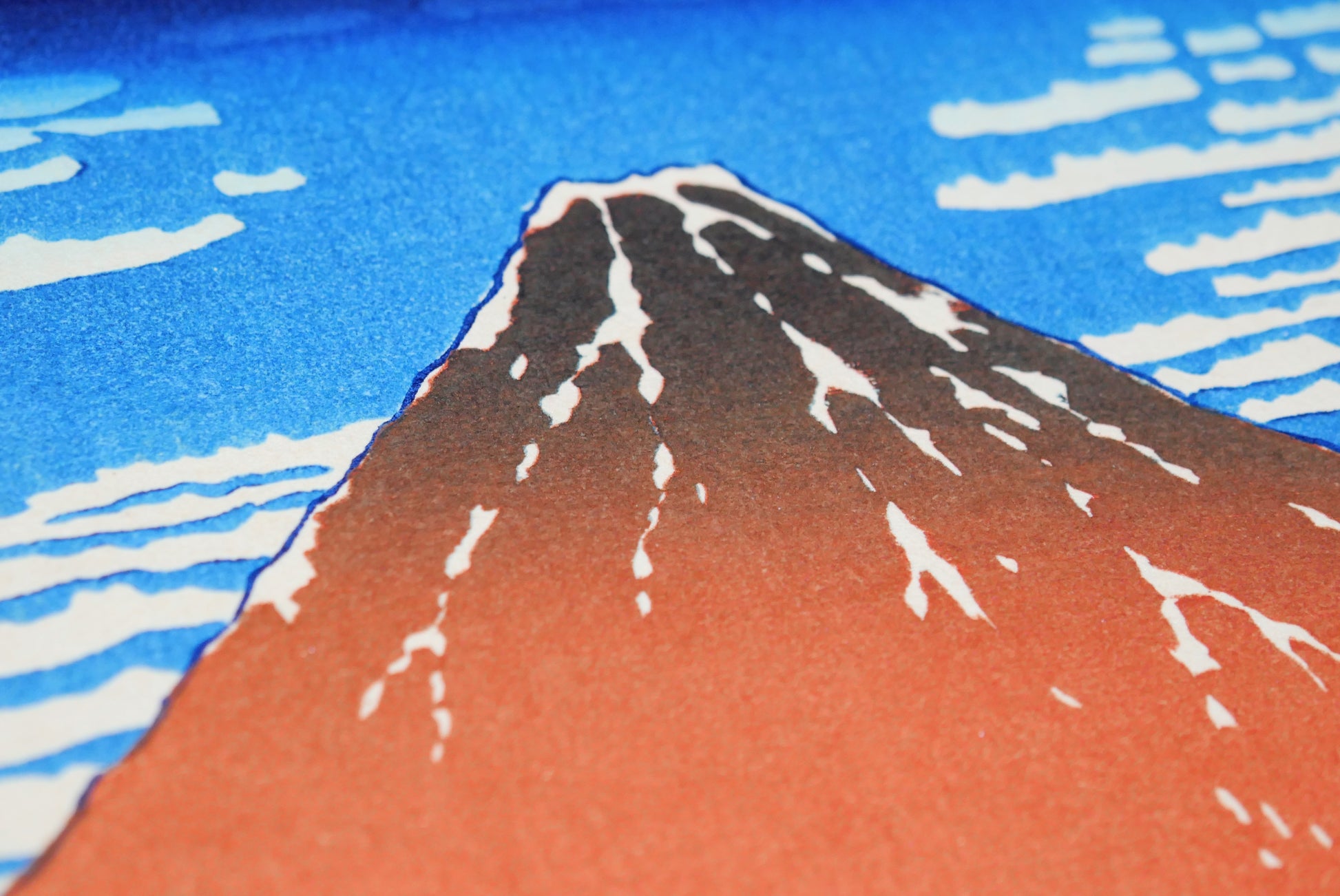 Gros plan sur le sommet du Fuji rouge et la texture d’impression sur bois de l’estampe de Hokusai.