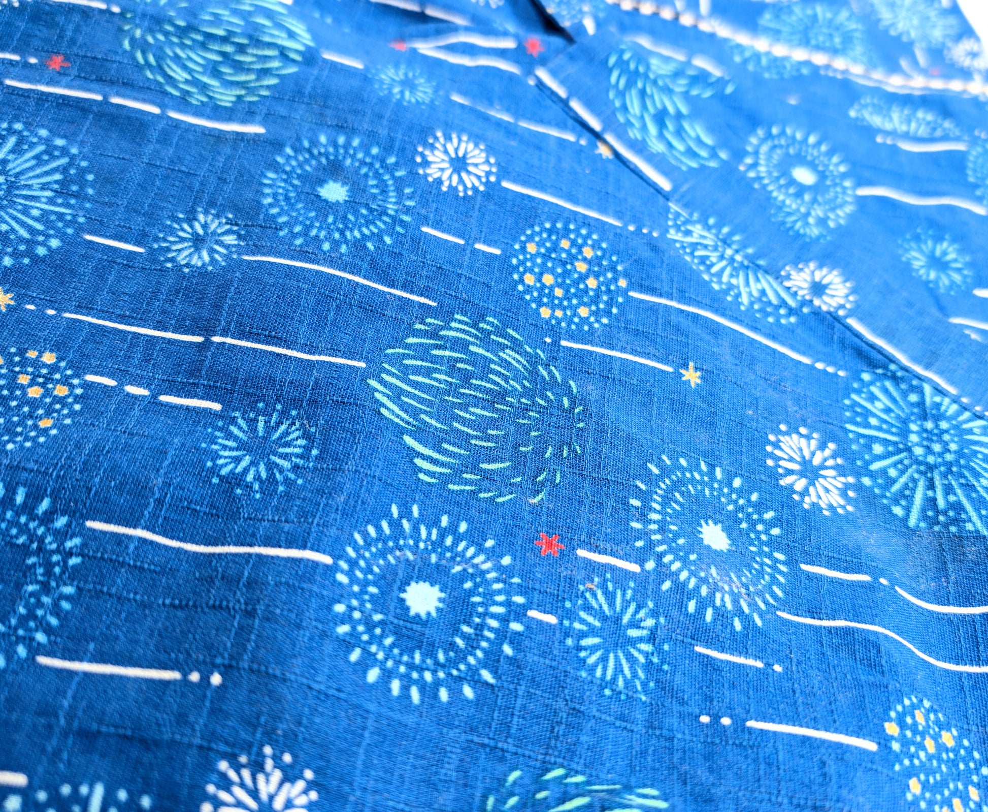 Détail du tissu de jinbei en coton bleu indigo, motif hanabi 花火 et lignes blanches.