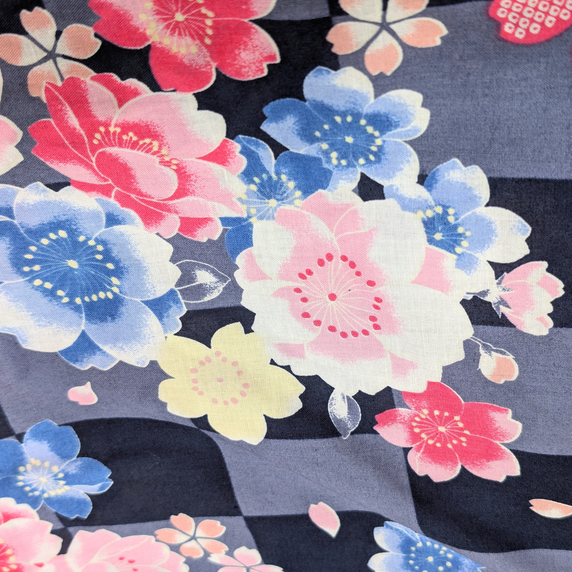 Gros plan du tissu coton d’un yukata japonais, fleurs de cerisier sakura sur damier ichimatsu gris noir