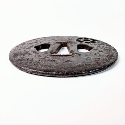 Vue générale d’une tsuba japonaise ancienne Ko-Tōshō en fer, de forme marugata, ornée d’un Kuyō-mon en sukashi.